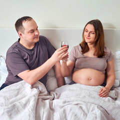 A man gives a pregnant woman wine, a concept of alcohol problems during pregnancy