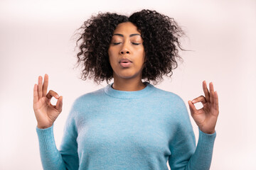 Calm african woman in blue relaxing, meditating. She calms down, breathes deeply with mudra om on...