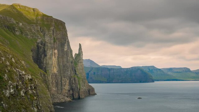 Time lapse of rock formation Trollkonufingur and fast moving clouds over the ocean, Vagar Faroe Islands
