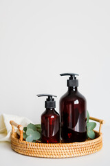Rattan tray with amber glass bottles of shampoo. Bath cosmetics set, SPA natural organic beauty products.