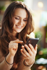 smiling woman in sunny day sending text message using phone