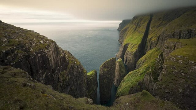 Time lapse of cliff and rock formation Dunnesdrangar and clouds over the ocean, birds flying arouind, Vagar Faroe Islands
