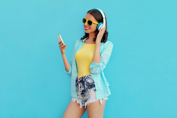 Portrait of happy smiling young woman with phone and wireless headphones listening to music on a...
