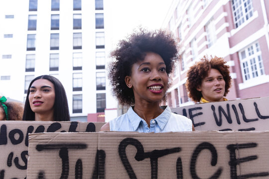 Three diverse male and female protesters on march holding homemade protest signs and smiling