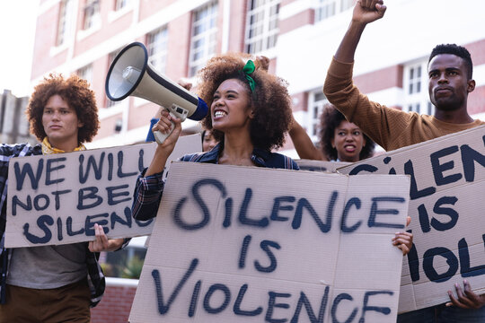 Diverse male and female protesters on march holding protest signs, raising fists and using megaphone