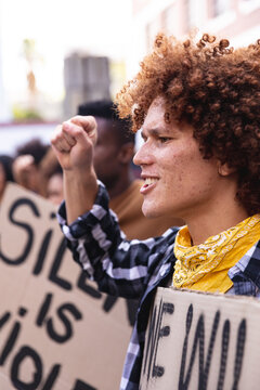 Mixed race man shouting with protesters on march holding signs and raising fists