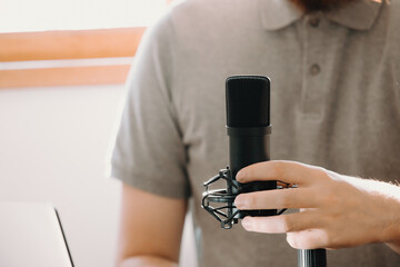 Close up of a streaming microphone while a man holds a phone working streaming with copy space...