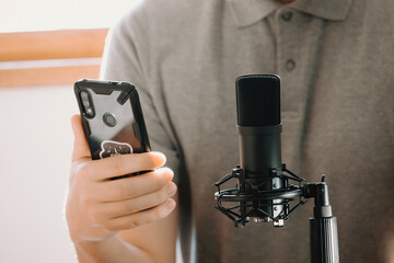 Close up of a streaming microphone while a man holds a phone working streaming with copy space...