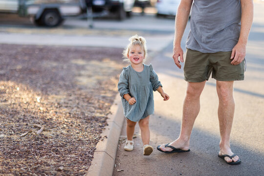 little girl boldly stepping out with dad along edge of road