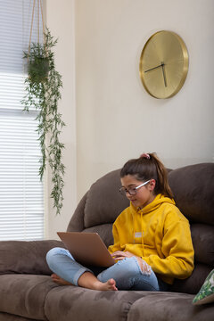 Girl sitting on sofa with laptop on crossed legs