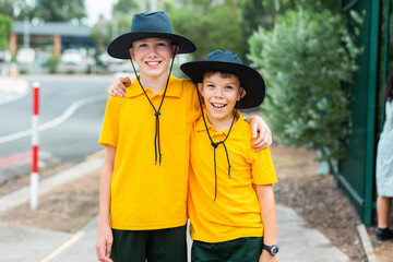 Happy brothers standing together before school wearing hats