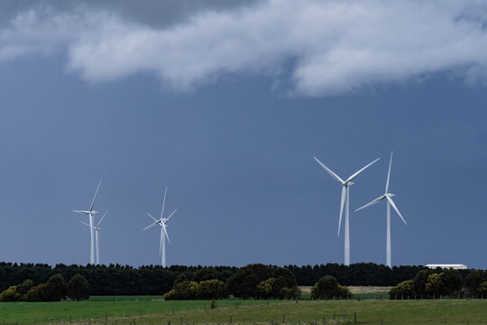 Dark stormy skies hovering over tall wind turbines
