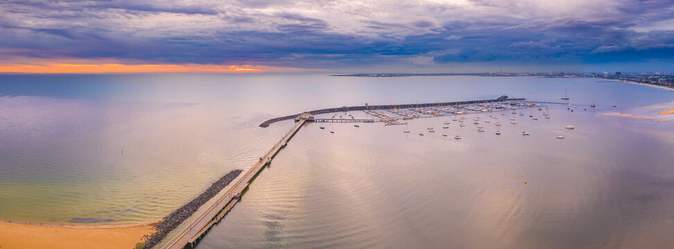 Aerial view of a jetty and breakwater on a calm bay at sunset