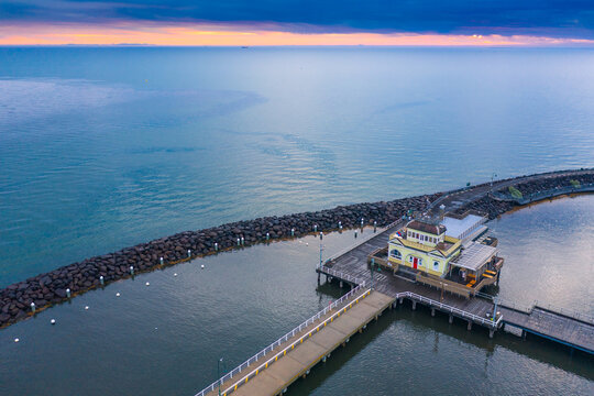 Aerial view of a pavilion on a jetty on a calm bay at sunset