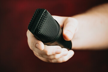 A hand grabbing a microphone over a red background