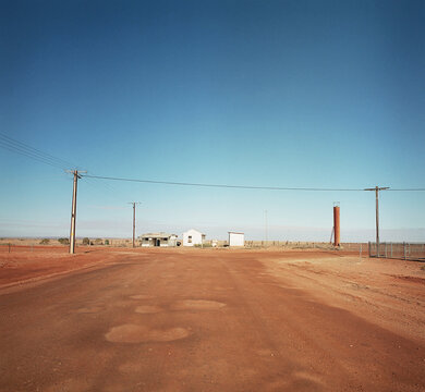 Dirt road in remote town with houses and power lines