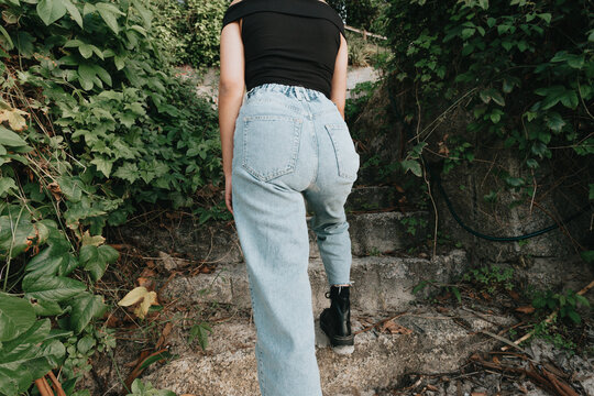 Back Part Of A Woman Wearing Mom Jeans Surrounded By Plants And Modern Style