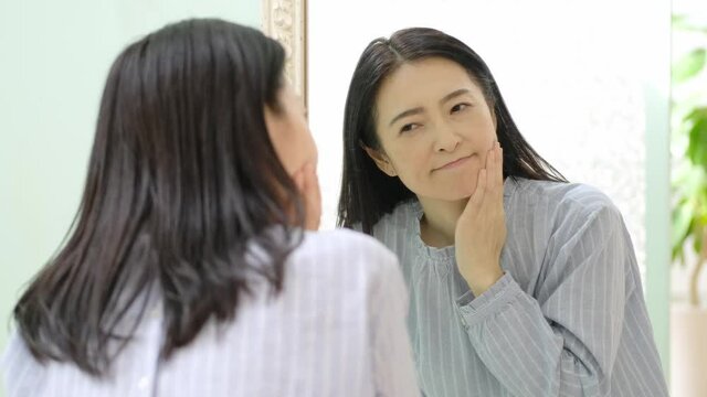 鏡を見てお肌をチェックする女性