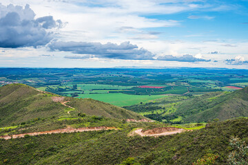Landscape of hills with a view to farms, fields and dirt roads down the hill. Beautiful landscape view of MG-341 road at São Roque de Minas, MG, Minas Gerais - Brazil.