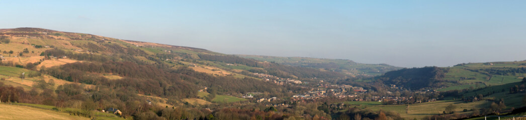 Fototapeta na wymiar panoramic view of the calder valley in west yorkshire with the town of mytholmroyd surrounded by fields, woods and moorland