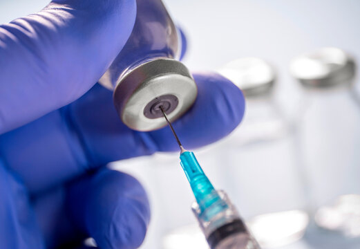 Close-up of gloved hand holding Covid-19 vaccine vial and syringe