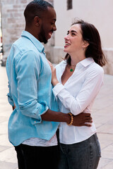 couple of young multiethnic guys laughing as they walk through the streets of the city, black guy and white girl in love