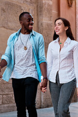couple of young multiethnic guys laughing as they walk through the streets of the city, black guy and white girl in love