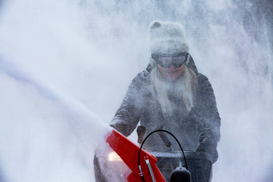 Senior woman clearing snow using snowblower