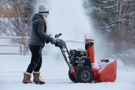Senior woman clearing snow using snowblower
