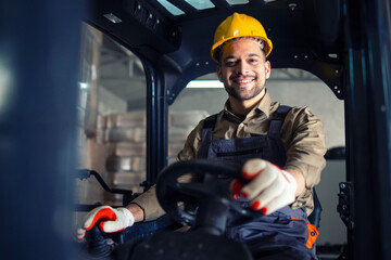 Portrait of smiling caucasian forklift operator driving machine and working in storehouse.