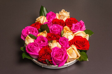 Composition of fresh multicolored roses on ceramic stand