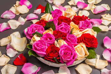 Composition of fresh multicolored roses on ceramic stand