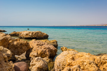 sunny landscape of the Red Sea coast in Sharm El Sheikh, Hadaba, with blue-turquoise water and orange-yellow-black stones
