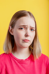 Young woman is upset. Closeup Emotional portrait of teenager girl with grimace of crybaby displeasure sad tired face. Sorry sad lady portrait isolated over yellow color background.