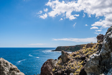 Mountain hiking trail with cliff rocks with selective focus by the Atlantic Ocean on Terceira Island - Azores PORTUGAL