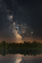 Fototapeta premium Milkyway rising over some Trees and Water/River