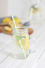 Vertical closed shot of a lemon and mint drink. White and unfocused background