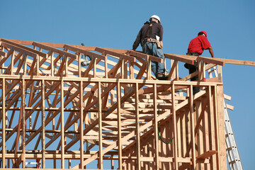 unidentifiable construction workers work on framing a building.