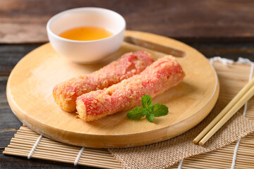 Deep fried crab sticks or surimi on wooden board eating with chili sauce