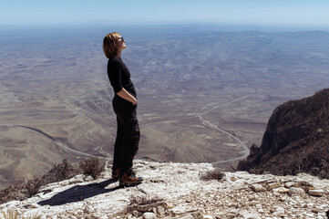 a female hiker standing on the rock with the view over the valley