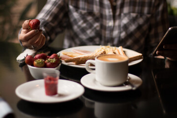 Table with breakfast in restaurant with fresh strawberries, coffee, toast