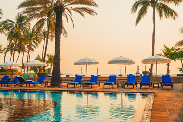 palm tree with umbrella chair pool in luxury hotel resort at sunrise times