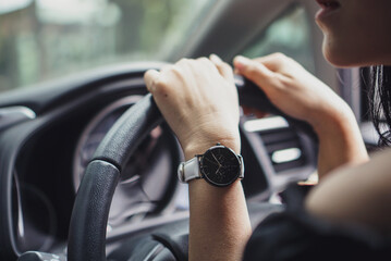 Hand of woman wearing watch holding car steer