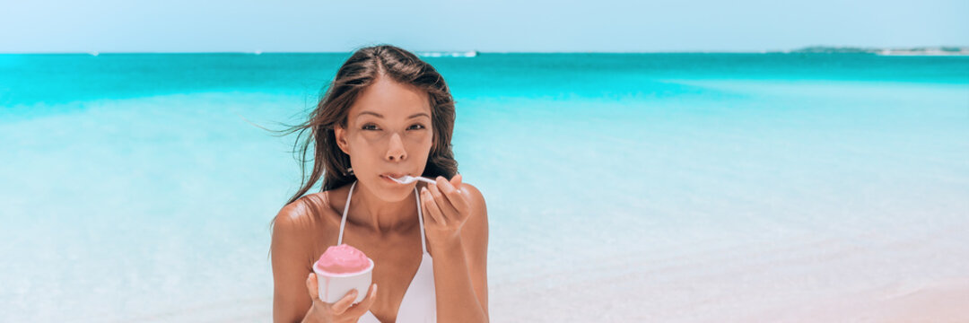 Ice cream dessert on beach. Happy Asian woman eating delicious frozen fruit yogurt or Acai smoothie bowl healthy food. Panoramic banner of blue ocean background.