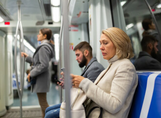 Portrait of female passenger using mobile phone in subway. High quality photo