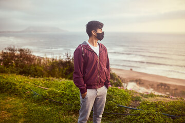 Naklejka na ściany i meble Hombre joven descansa en un parque durante un atardecer de verano. Hombre mirando al horizonte del mar. 