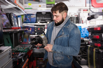 Positive glad male is standing with new impact wrench in tools store