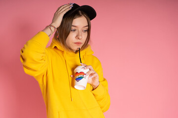 Girl drinks from a cup of rainbow LGBT coffee