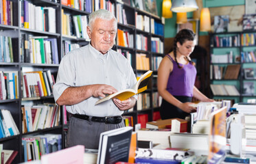 Mature male customer is looking new book for reading in free time in bookshop