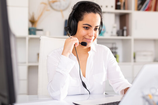 Smiling young female operator talking with customer using headset at company office